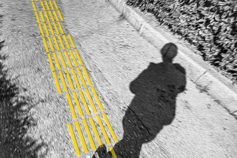 Ombra di una persona che cammina su una pavimentazione tattile gialla