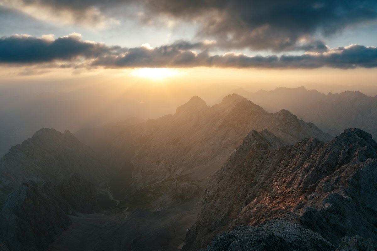 Raggi di sole che attraversano le nuvole sopra le cime di una montagna