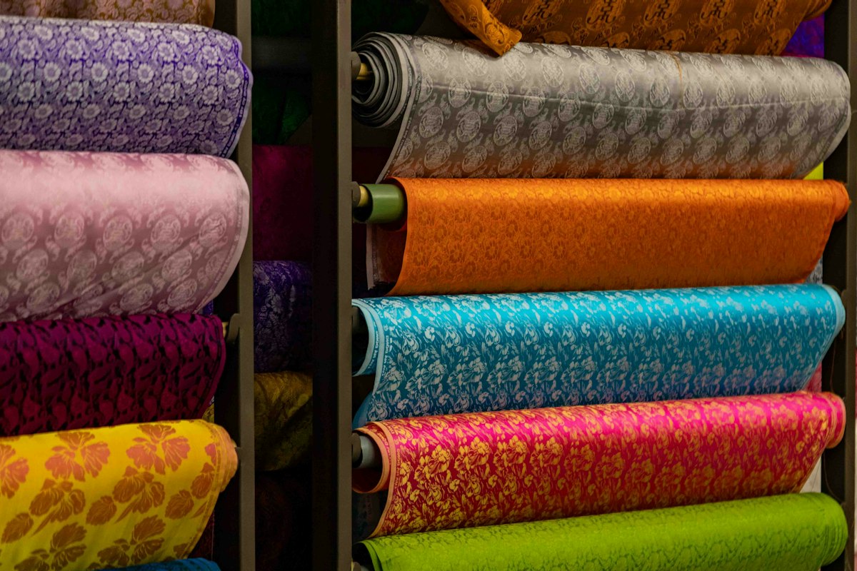 Pile di rotoli di tessuto colorato e a motivi su scaffali